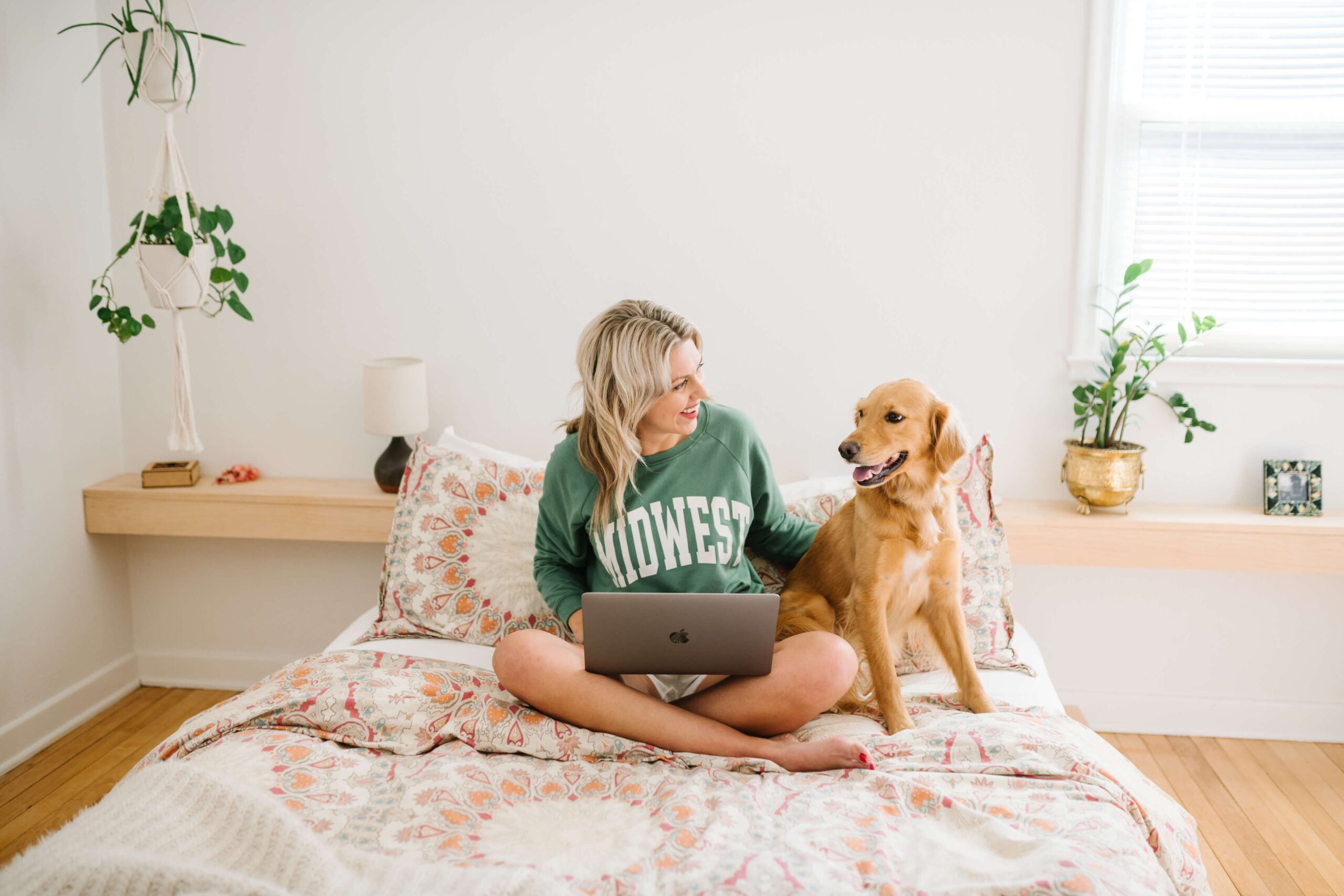 Sarah Klongerbo working on marketing copy with her dog Pali on a bed